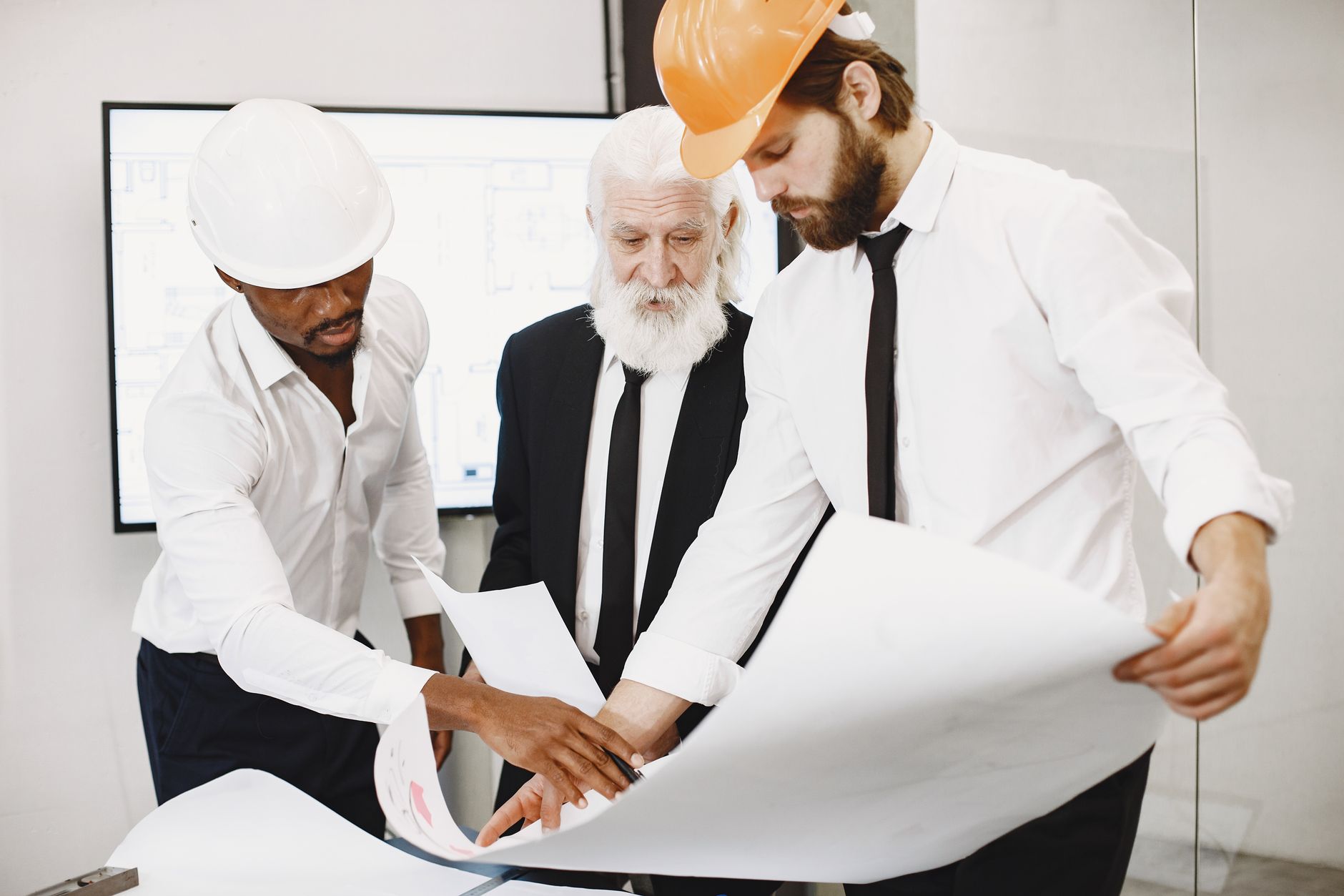 Three architects in an office reviewing plans together.